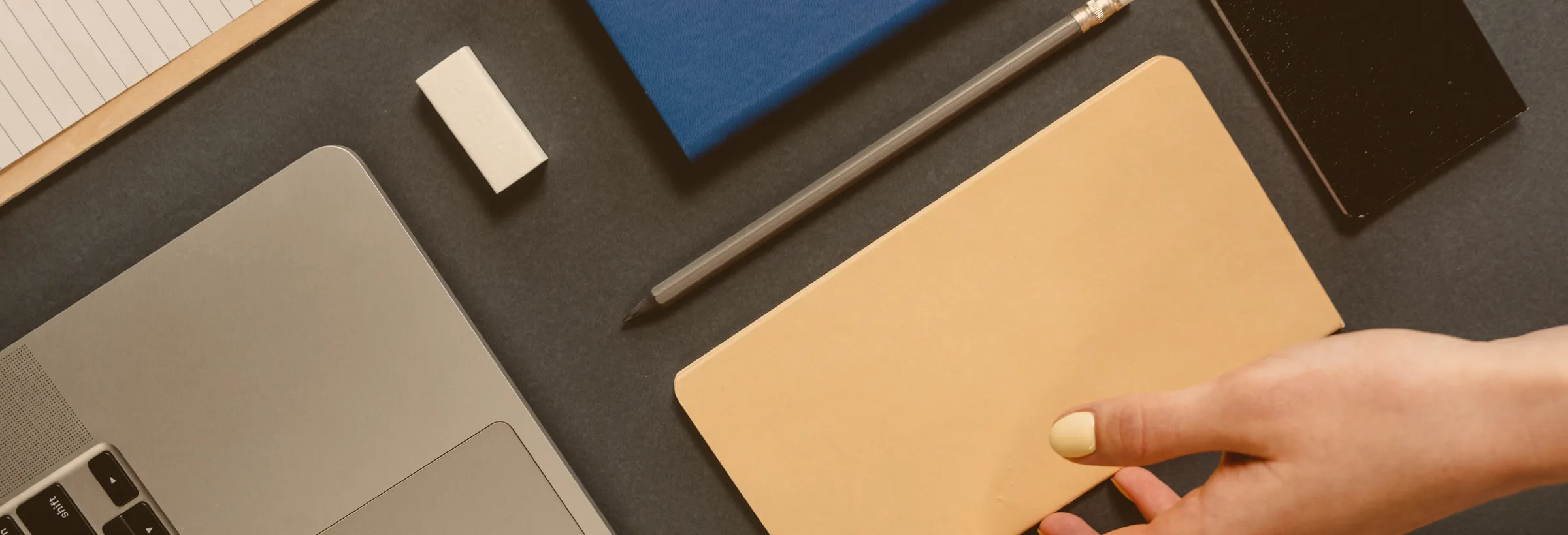 Schreibtisch von oben mit Kraftpapier-Umschlag neben einem Laptop