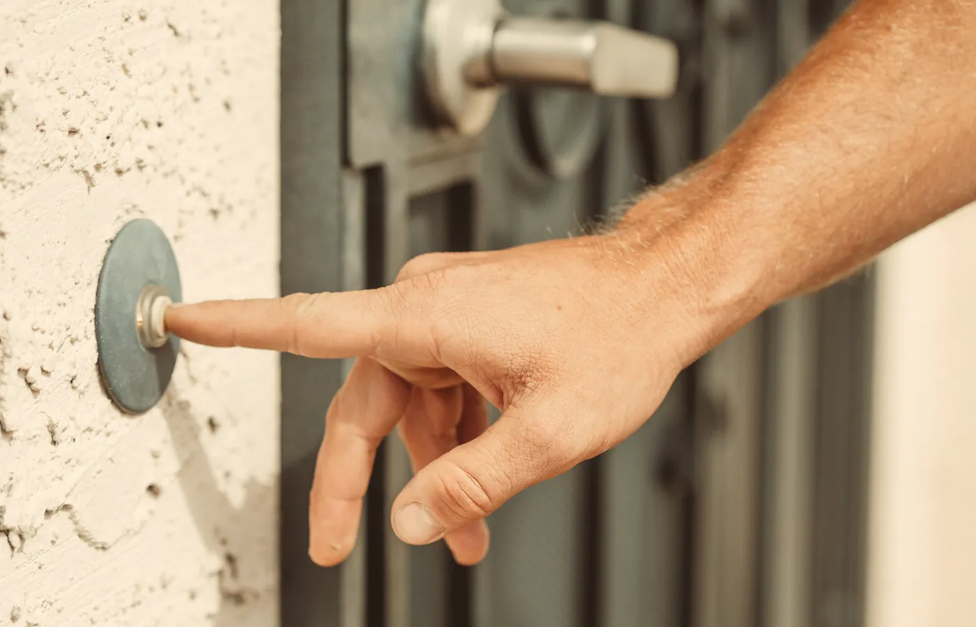 Finger drückt einen Klingelknopf am Hauseingang