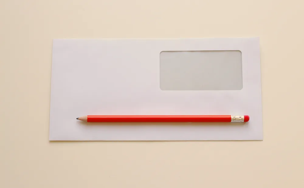 Weißer Fensterumschlag mit rotem Bleistift auf hellem Grund