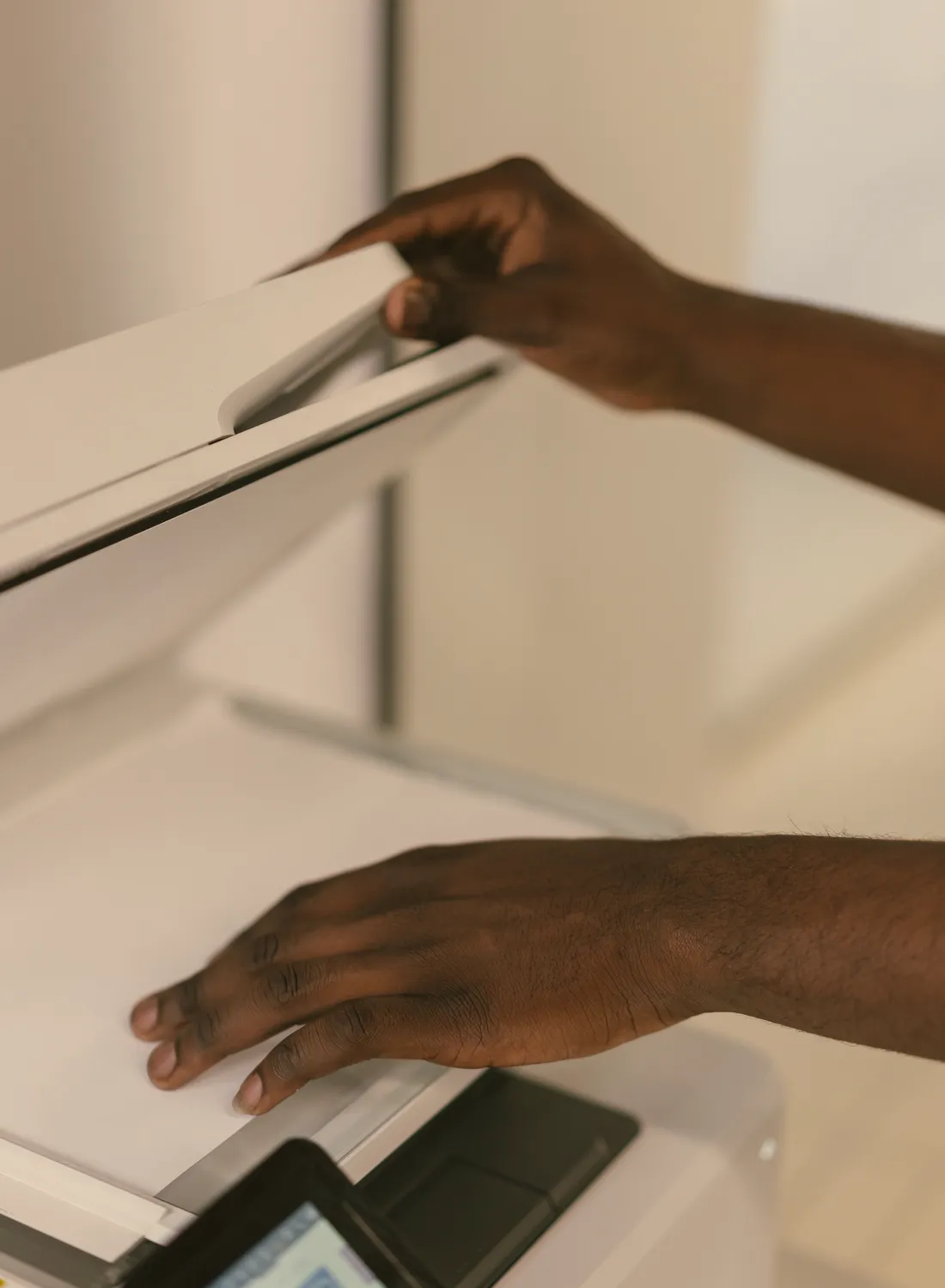 Hände legen ein Dokument auf die Glasfläche eines Scanners